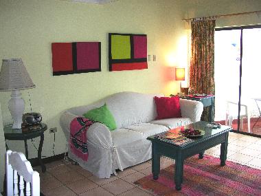 Living room area with balcony at far right. The sofa  folds out to a double bed for extra sleeping.