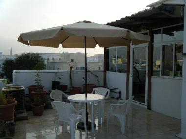 Big terrace with large umbrella and garden furniture and grill