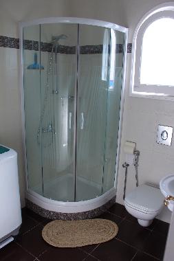 Bathroom with showercabine and semi-automatic washing machine.