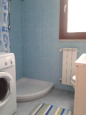 Bathroom with shower and washing machine in new holiday apartment. Marconia, Basilicata, Italy