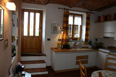 The kitchen is fully equipped. The door leads to the backyard garden