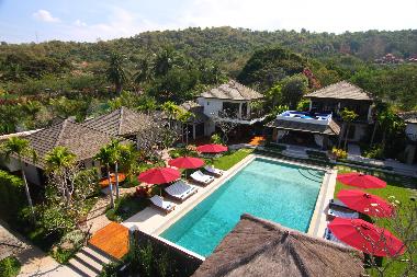 The pool is set amidst lawns with a tropical backdrop