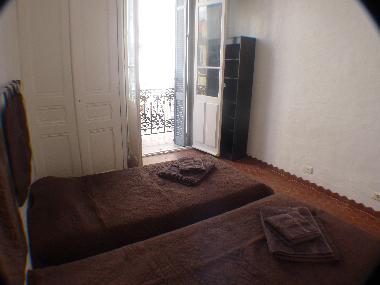 bedroom with 2 single beds built in cupboards and balcony